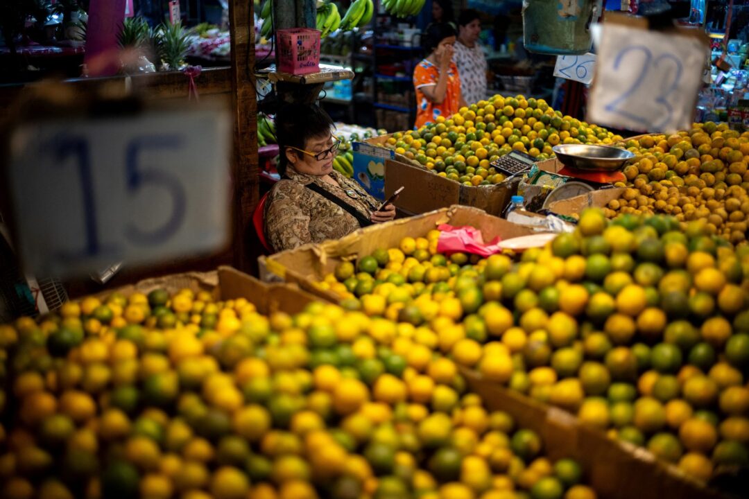 A vendor looks at a mobile phone at her fruit stall at a market as Thailand is to inject $15.2 bln into economy next year through its digital wallet policy, in Bangkok, Thailand, 2 October 2023 (Photo: Reuters/Athit Perawongmetha).